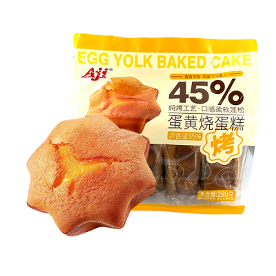 一块星形的 Aji 蛋黄烧蛋糕摆放在其包装袋前，展示其烘烤后的金黄成色和绵密质地。