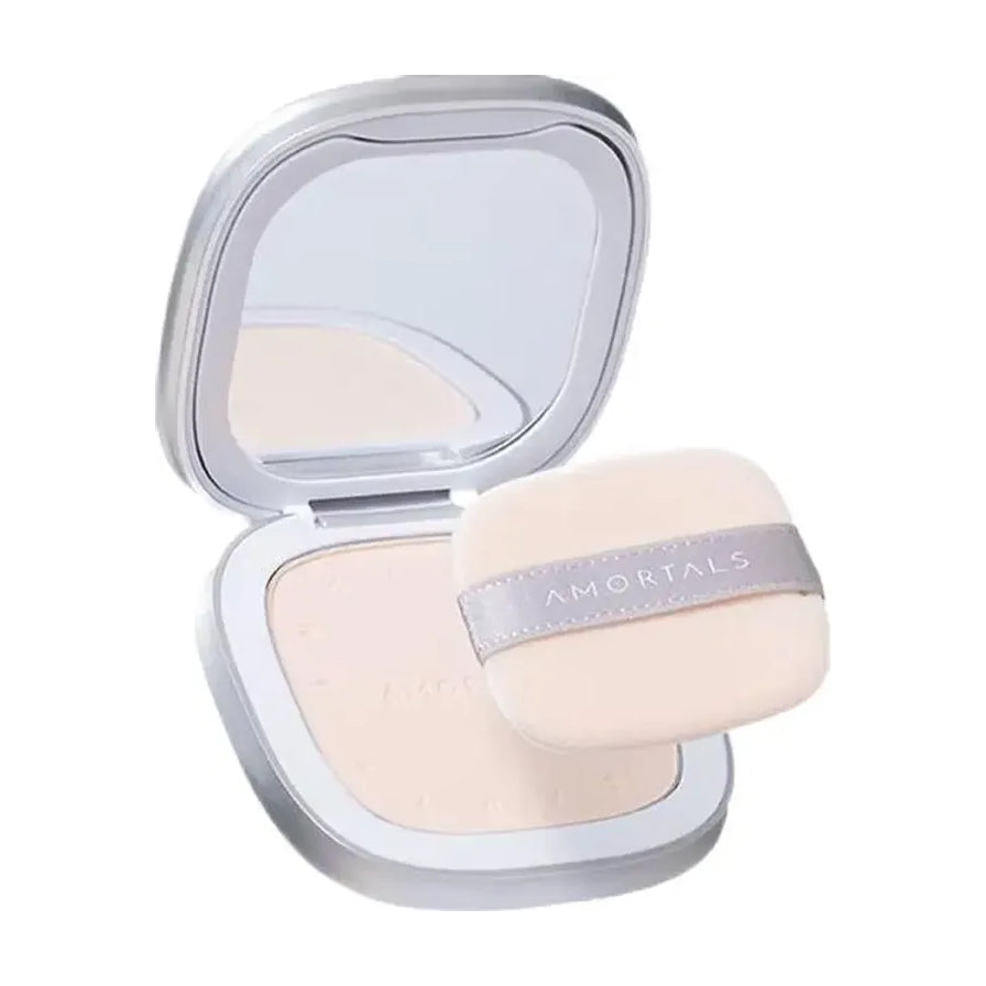 AMORTALS 尔木萄蜜粉饼打开状态，展示银色方形外壳、内置镜子及带有品牌标识的米色粉扑。