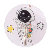 宇航员卡通图案圆形无痕粘钩特写，白色底座配黄色星星装饰，透明挂钩细节清晰可见。