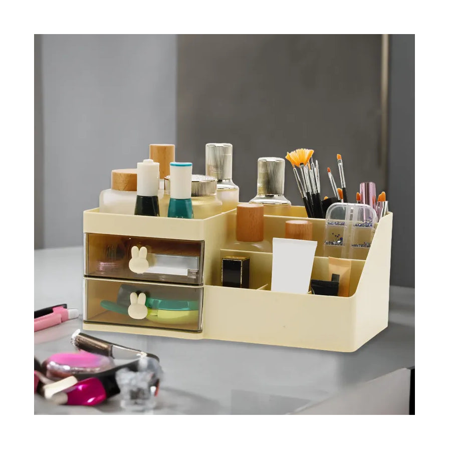 米黄色桌面收纳盒侧面视角，展示双抽屉结构和多格分区，前方桌面上散落着口红、指甲油等彩妆用品。