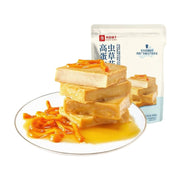 良品铺子高蛋白虫草花鱼豆腐，白色盘中叠放着四块淋有鸡汁的鱼豆腐，点缀着橙色虫草花，背景为产品包装袋。