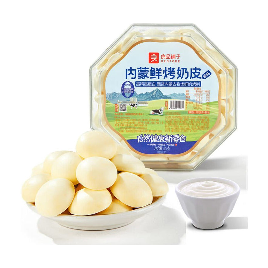 良品铺子内蒙古鲜烤奶皮盒装，前方摆放着一盘圆润酥脆的奶皮和一小碗鲜奶，展示产品质感。