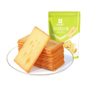 良品铺子日式岩烧芝士脆，白色圆盘中整齐叠放的薄脆饼干，背景为绿色包装袋。