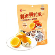 良品铺子鲜卤鹌鹑蛋香卤味包装袋，前方白色圆盘中摆放着剥壳后的Q弹鹌鹑蛋，展示蛋黄切面，背景为独立小包装。