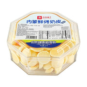 良品铺子内蒙鲜烤奶皮原味 65g 盒装俯视图，透明八角形塑料盒内装满淡黄色圆形奶片，标签可见营养成分表。