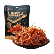 良品铺子五香味灯影牛肉丝，黑色包装袋前摆放着一盘色泽红亮、丝丝分明的牛肉丝，质地透光可见。