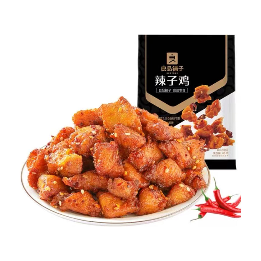 良品铺子辣子鸡，盘中盛满裹着芝麻和辣椒碎的紧实鸡肉块，背景为黑色包装袋和新鲜红辣椒。