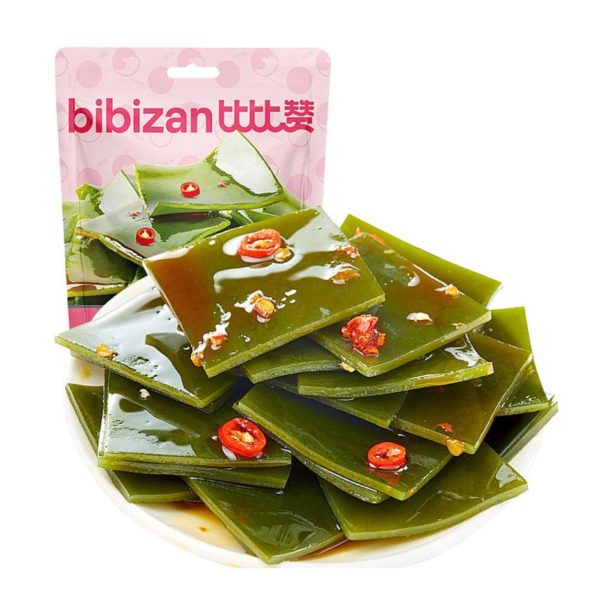 比比赞香辣海带片，白色圆盘中堆叠着裹满红油和辣椒圈的翠绿海带片，背景为粉色品牌包装袋。