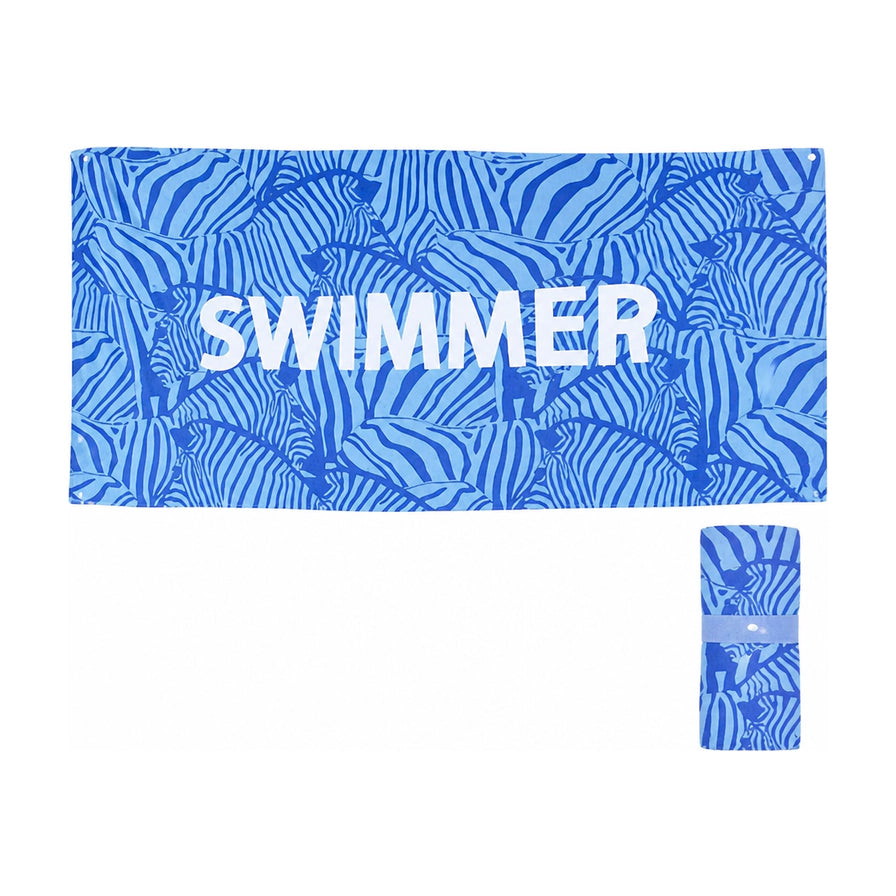 白色背景下展示的蓝色斑马纹沙滩浴巾，印有SWIMMER字样，右下角展示其折叠收纳后的圆柱状形态。