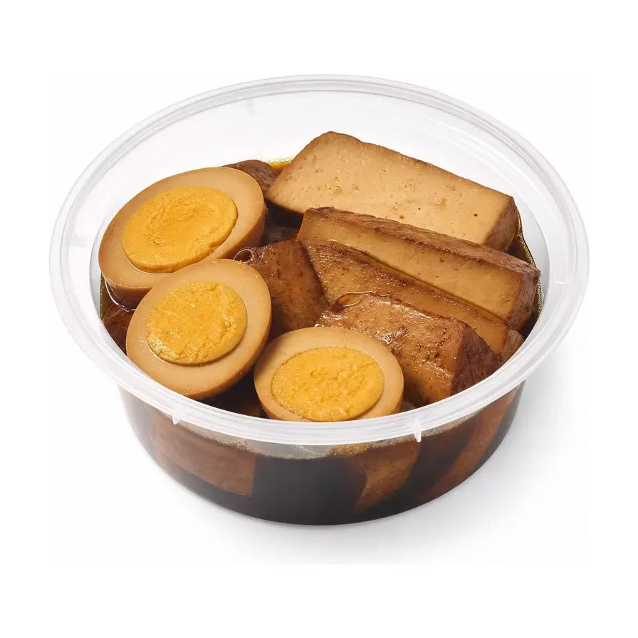 透明圆盒盛装的卤鸡蛋和卤豆干，鸡蛋切半露出绵密蛋黄，豆干厚实吸饱卤汁，整体呈现浓郁的酱褐色。