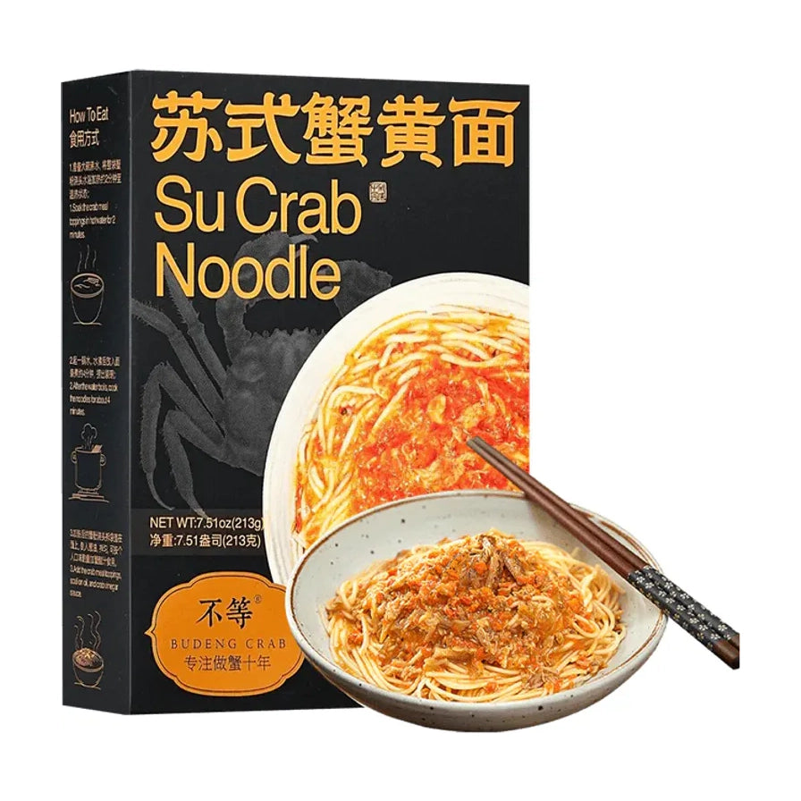 不等苏式蟹黄面黑金版包装盒与成品展示，黑色盒身印有金色中英文字样及食用方式图示，前方摆放一碗拌好蟹粉的面条和一双筷子。