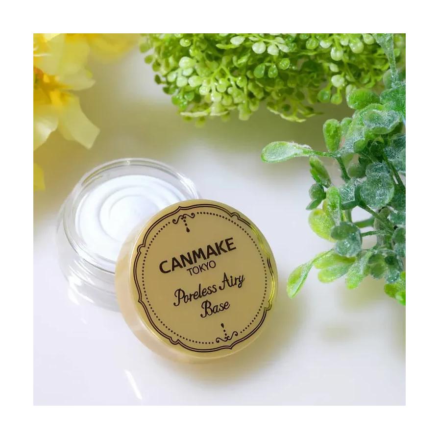 CANMAKE 毛孔隐形膏开盖平放图，背景搭配绿色植物与黄色花朵，展示清新自然风格。