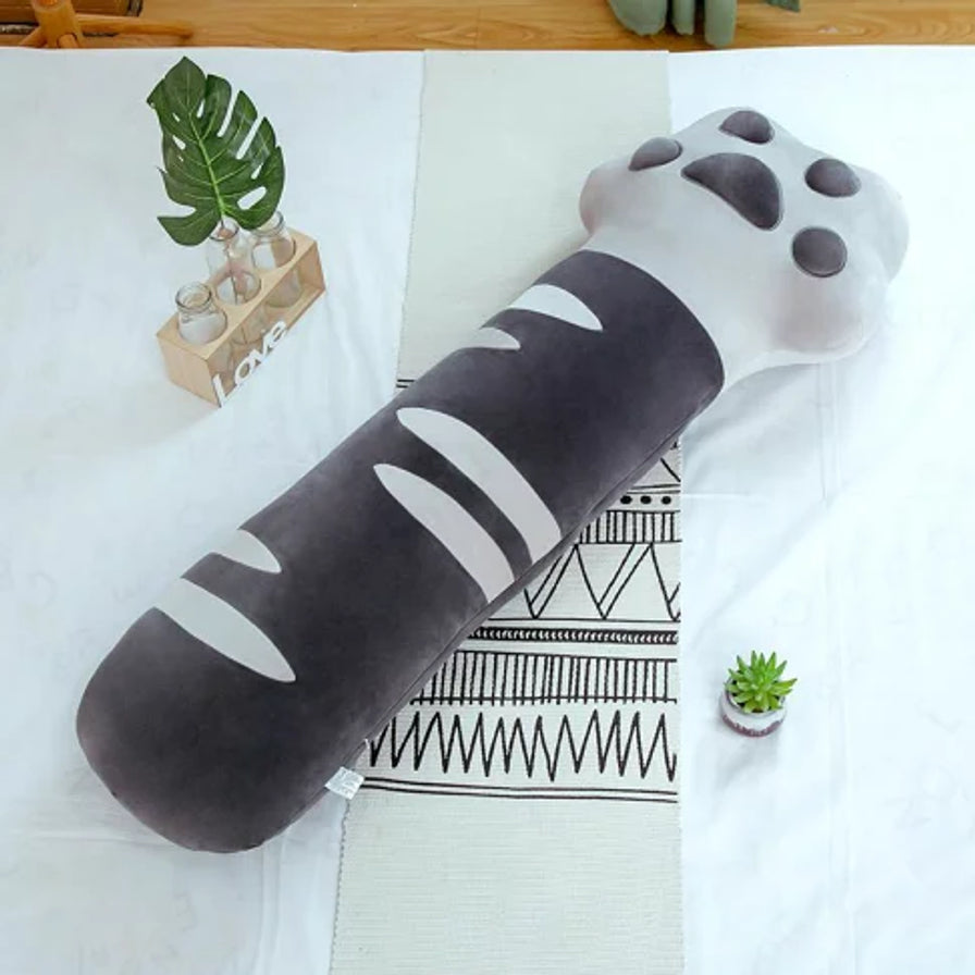 灰色猫爪长条枕平铺在白色床单上的俯视图，旁边配有绿植装饰，展示其柔软的质感。
