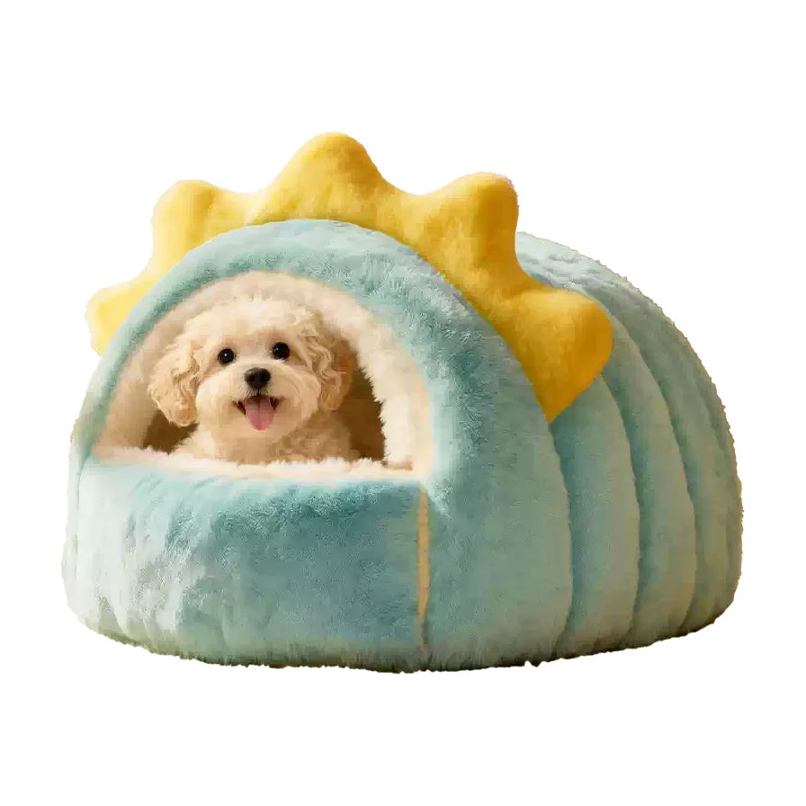 一只白色小狗坐在蓝绿配色、带有黄色太阳装饰的半封闭式宠物狗窝中，背景为纯白色。