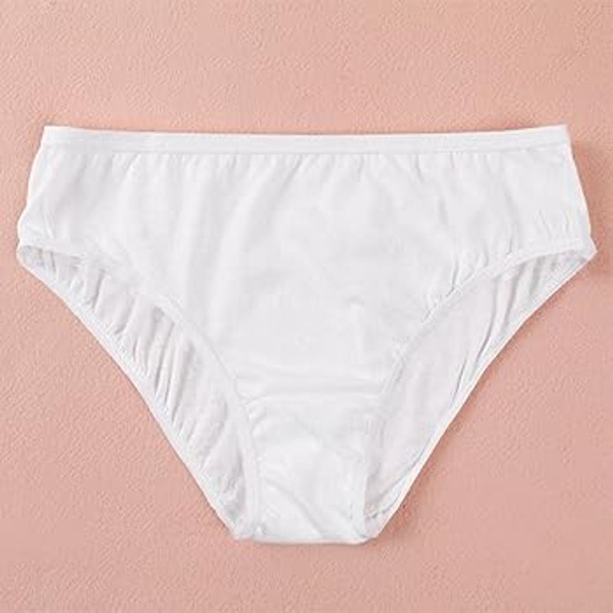 白色纯棉一次性女士三角内裤，平铺于粉色背景上，展示内裤的剪裁和柔软质感。