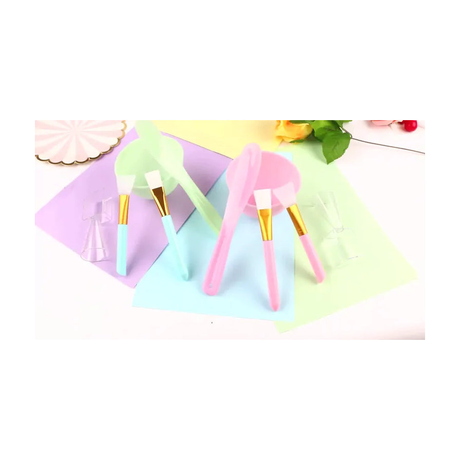 DIY 面膜工具套装平铺展示，包含粉色和绿色碗具及刷子，搭配彩色背景纸。