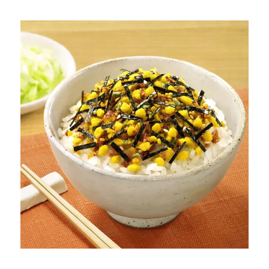 一碗白米饭，上面撒满了鸡蛋碎、海苔丝和芝麻组成的拌饭料，旁边放着木质筷子。