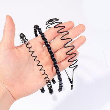 一只手托着三个黑色隐形金属波浪发箍，展示其细窄的螺旋结构和两端橡胶保护套。