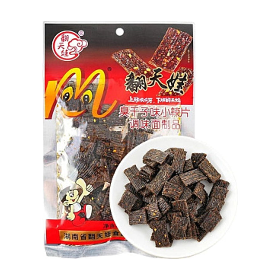 翻天娃臭干子包装袋与一盘深色块状辣条，包装上有翻天娃品牌标识和臭干子味小辣片字样。