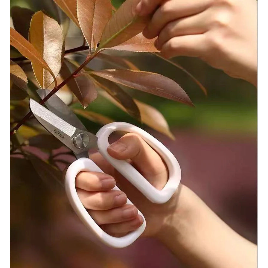 手持FaSoLa园艺剪修剪户外植物枝条的使用场景图。