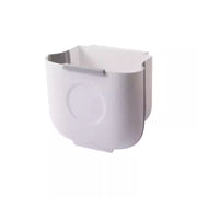 极简白色壁挂式可折叠垃圾桶正面图，展示挂在橱柜门上的节省空间设计