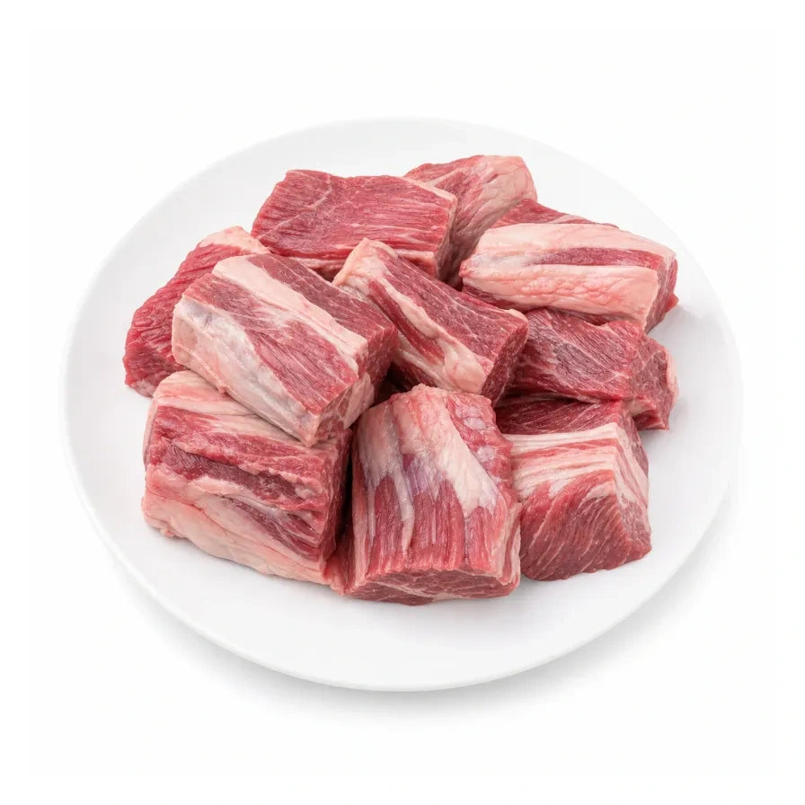 白色圆盘中盛放的切块新鲜牛腩，肉质纹理清晰，肥瘦相间，适合炖煮红烧。