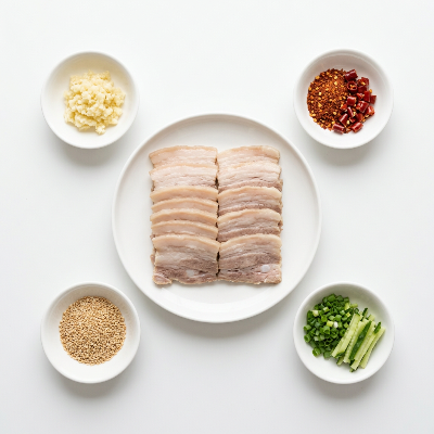 蒜泥白肉食材俯拍图，包含五花肉片、蒜泥、红油、芝麻、葱段和黄瓜