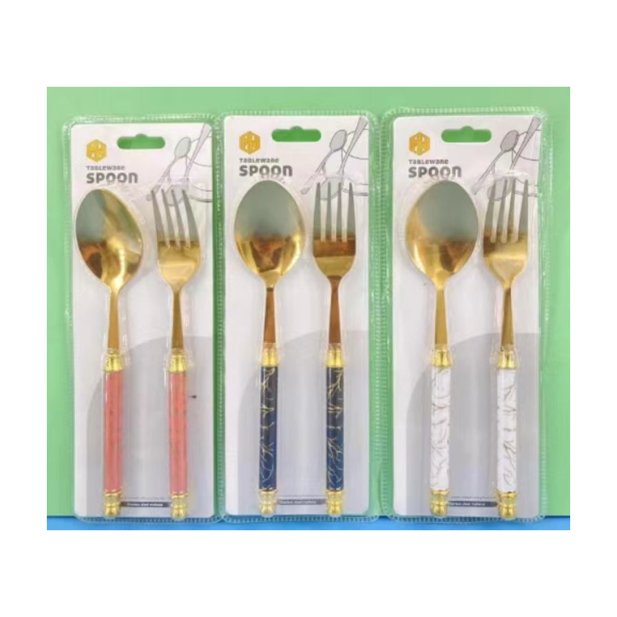 三套不同手柄颜色的金色勺叉餐具套装，包含粉色、蓝色和白色大理石纹理手柄，采用透明吸塑包装。