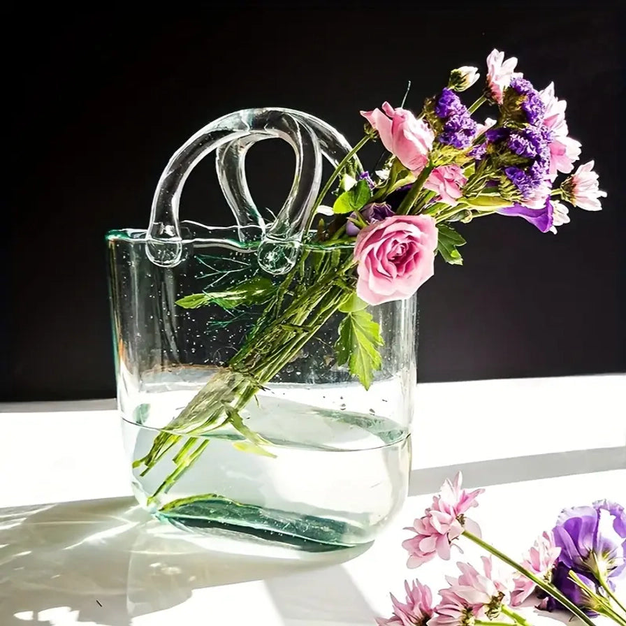 阳光照射下的手提包玻璃花瓶，瓶内盛水并插有紫色和粉色花束，光影效果通透。