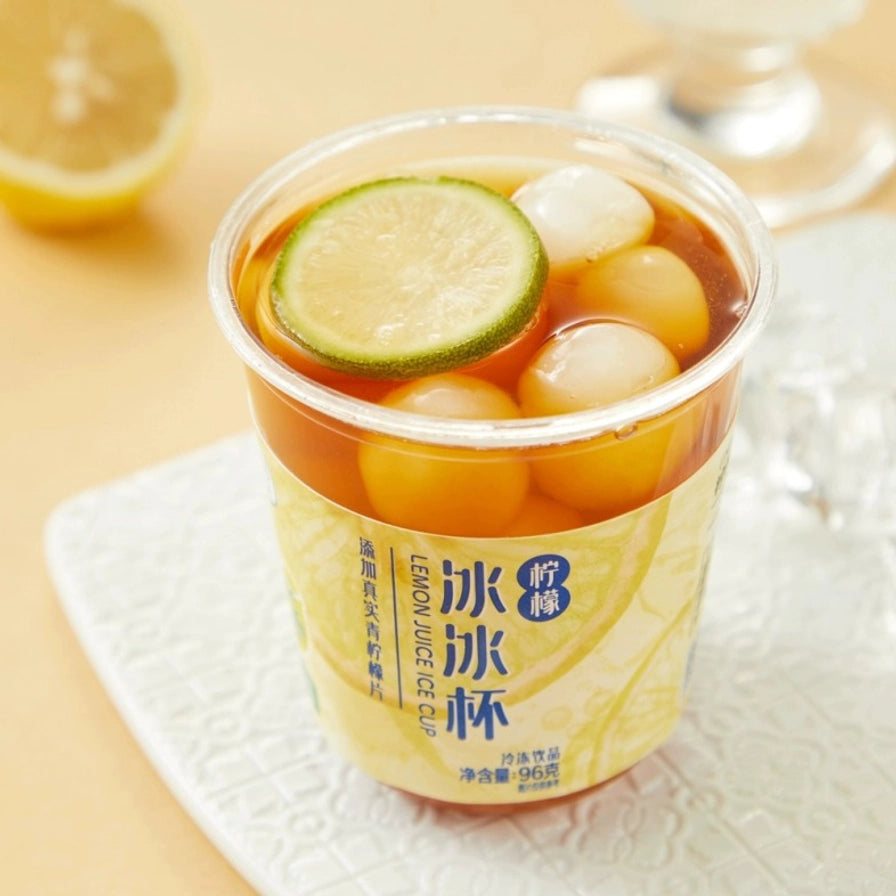 盒马柠檬冰冰杯特调展示，杯中加入茶饮后的俯视视角，可见顶部的青柠檬片和圆润的冰球。