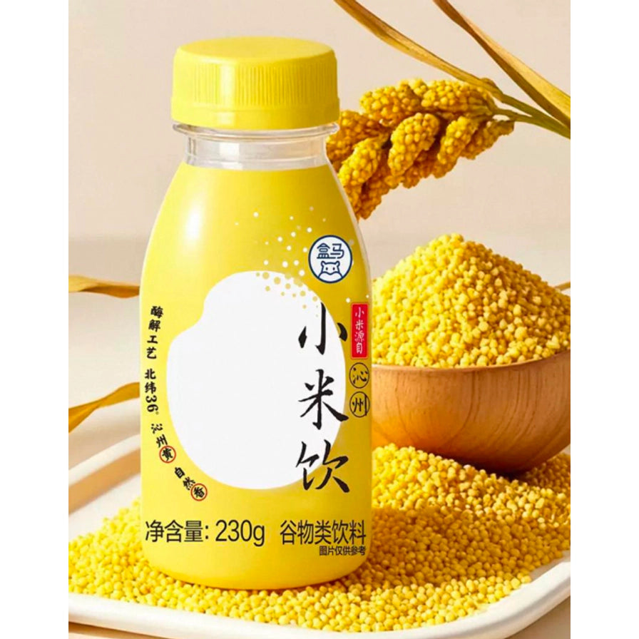 盒马小米饮230g瓶装，背景配有黄色小米颗粒及木碗，展示谷物原材。