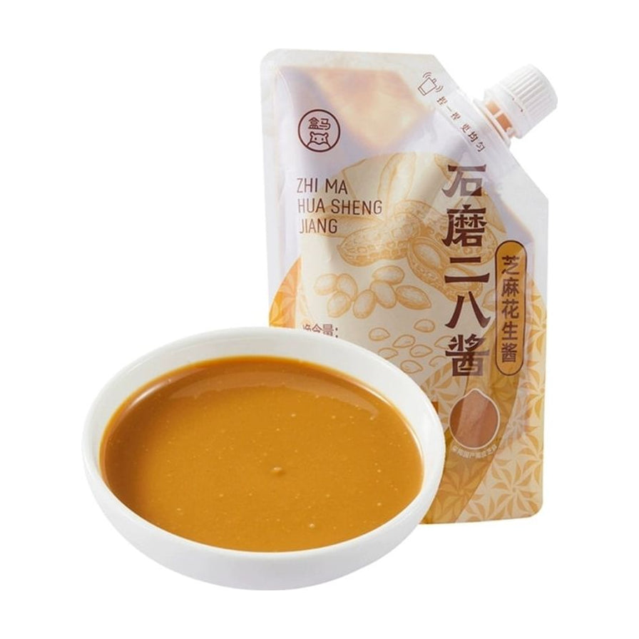 盒马石磨二八酱，旋盖挤挤装包装，前方摆放一小碗调好的浓郁芝麻花生酱。