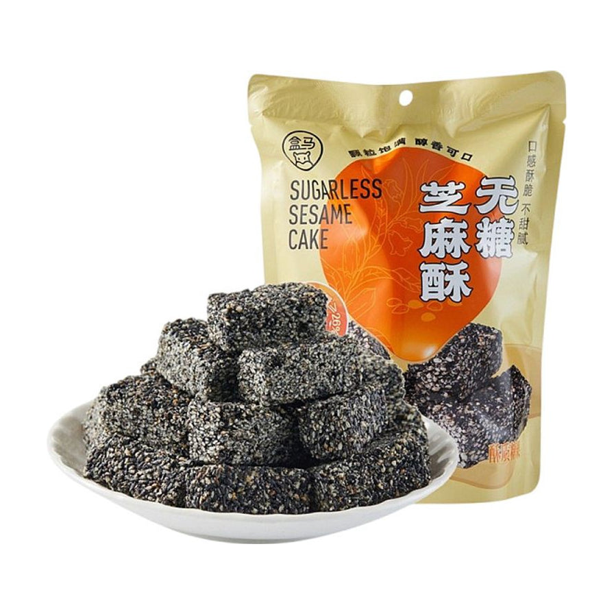 盒马无糖芝麻酥包装袋及一盘堆叠整齐的黑色芝麻酥块，展示酥脆质感。