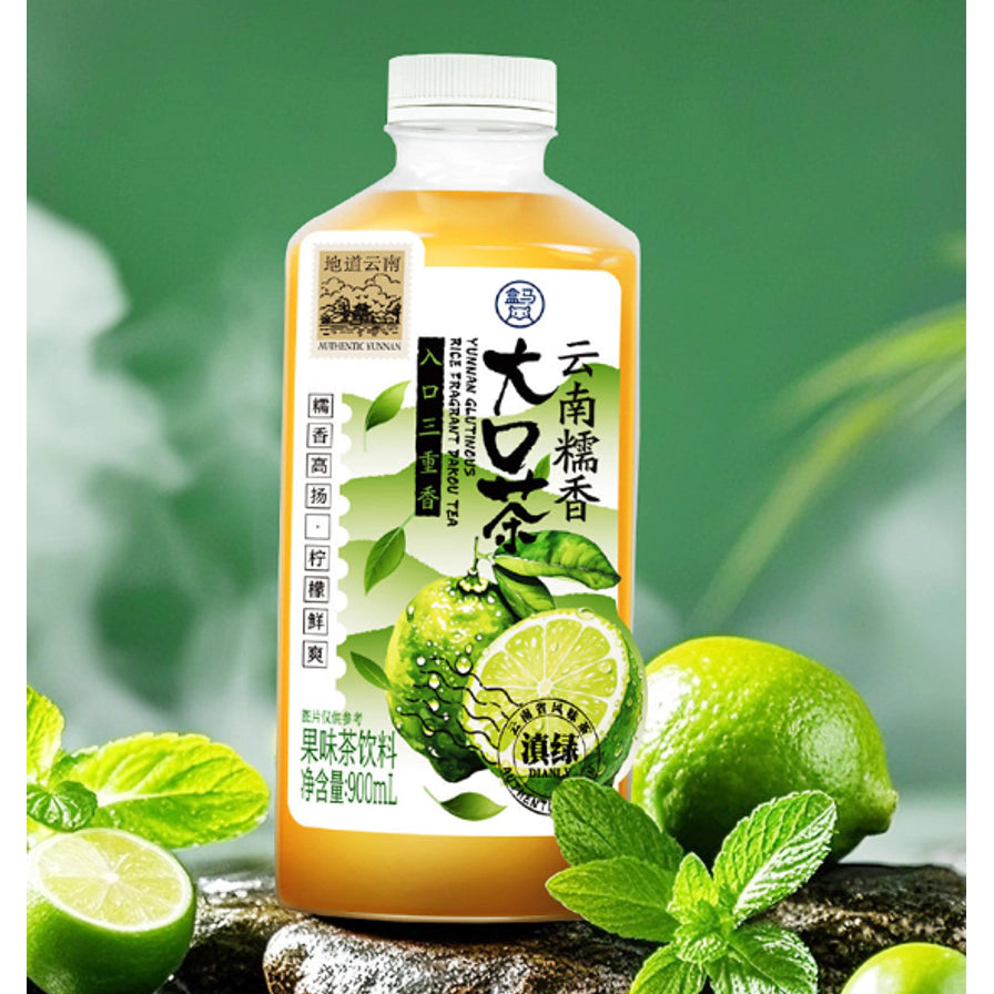 盒马云南糯香大口茶瓶装展示，背景配有新鲜柠檬和薄荷叶，突出清爽解腻的产品特性。