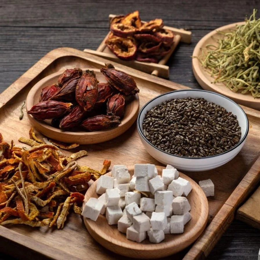 木质托盘上摆放的祛湿茶原材料近景，包含茯苓、陈皮、栀子和谷物等多种天然汉方配料。