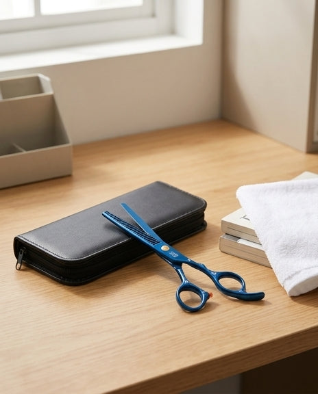 蓝色理发剪刀和黑色收纳包放置在木质桌面上，旁边有毛巾和书本的生活场景图。