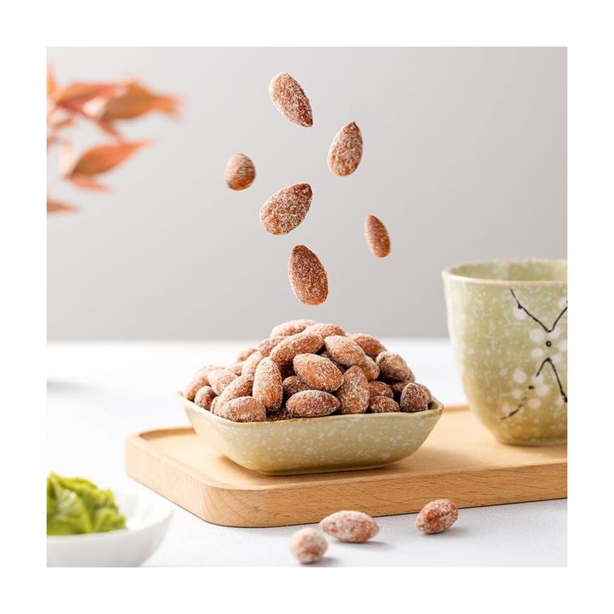 蜂蜜黄油巴旦木果仁落入碗中的动态场景，背景配有茶杯和木质托盘。