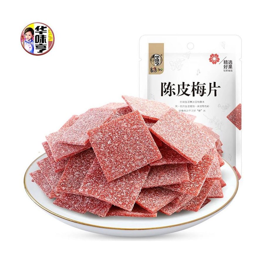 华味亨陈皮梅片，白色圆盘中堆叠着许多裹满糖霜的红色方形薄片，背景为产品包装袋。