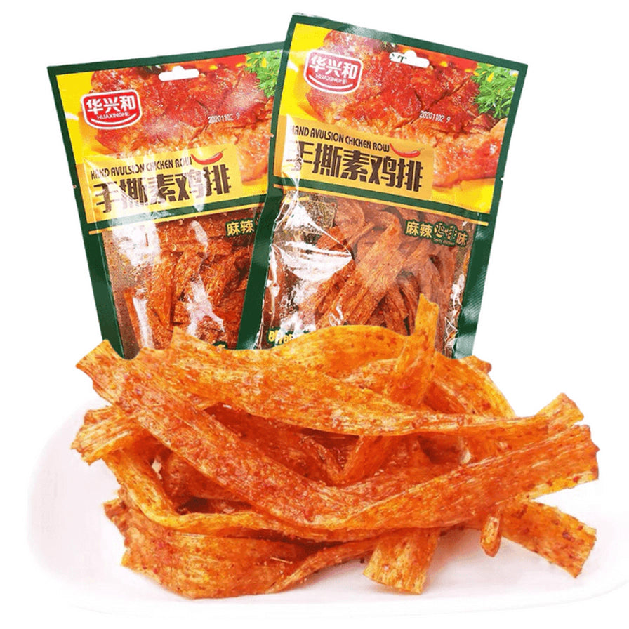 两袋华兴和手撕素鸡排包装及盘中散装的条状辣条，展示其金黄油亮的色泽。