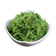 一小碗翠绿的日式海藻丝，点缀着白色芝麻，盛放在白色陶瓷碗中，背景为纯白色。