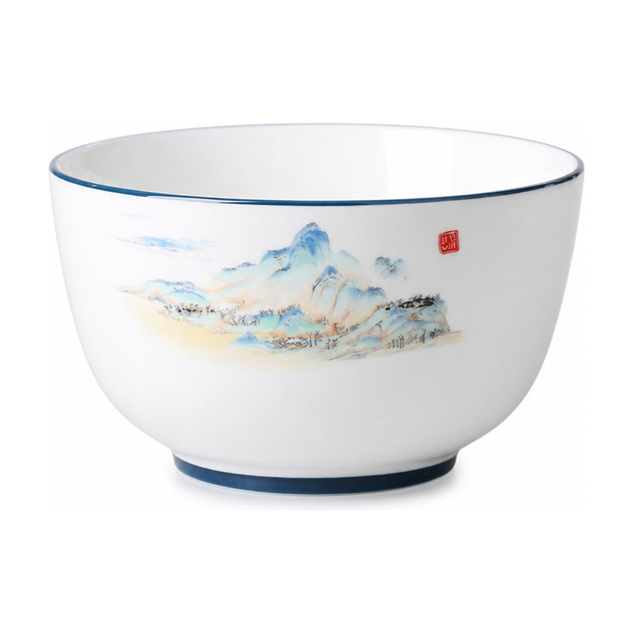 白色背景下的日式釉中彩陶瓷面碗，碗身印有淡雅的山水画图案，碗口边缘带有蓝色线条装饰。