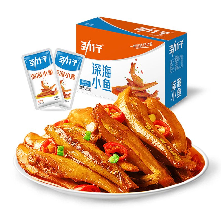 一盘色泽诱人的劲仔酱汁味深海小鱼，背景为对应的盒装及袋装产品。