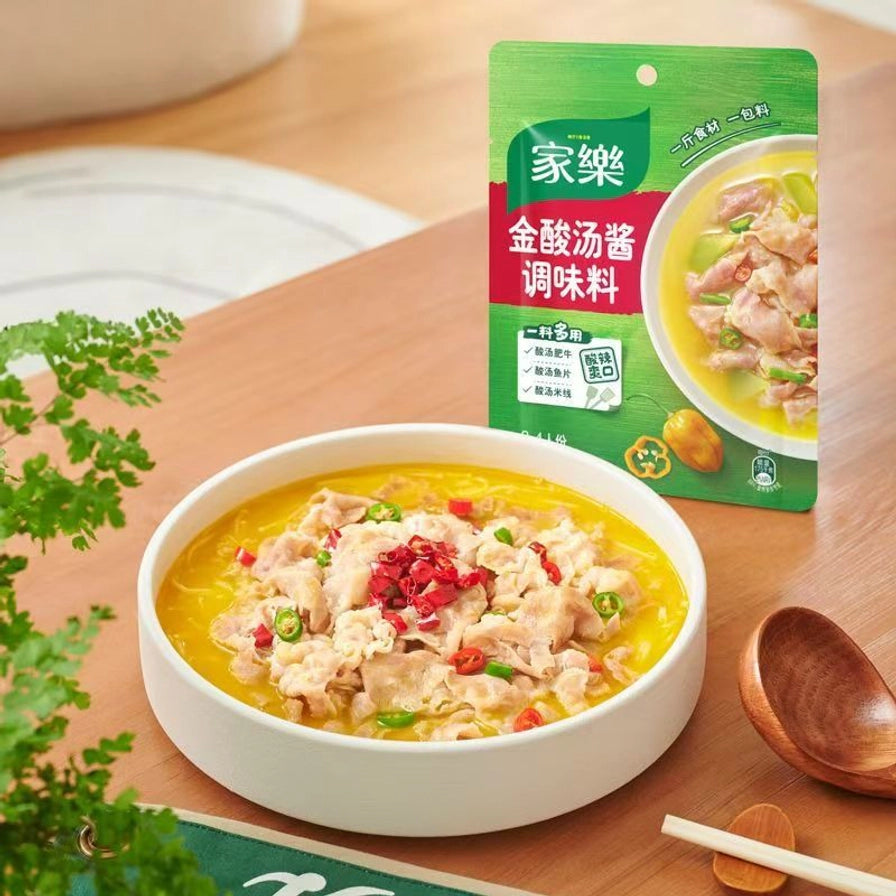 家乐金酸汤酱调味料包装与烹饪好的酸汤肥牛成品展示，色泽金黄，配有木勺和餐具。