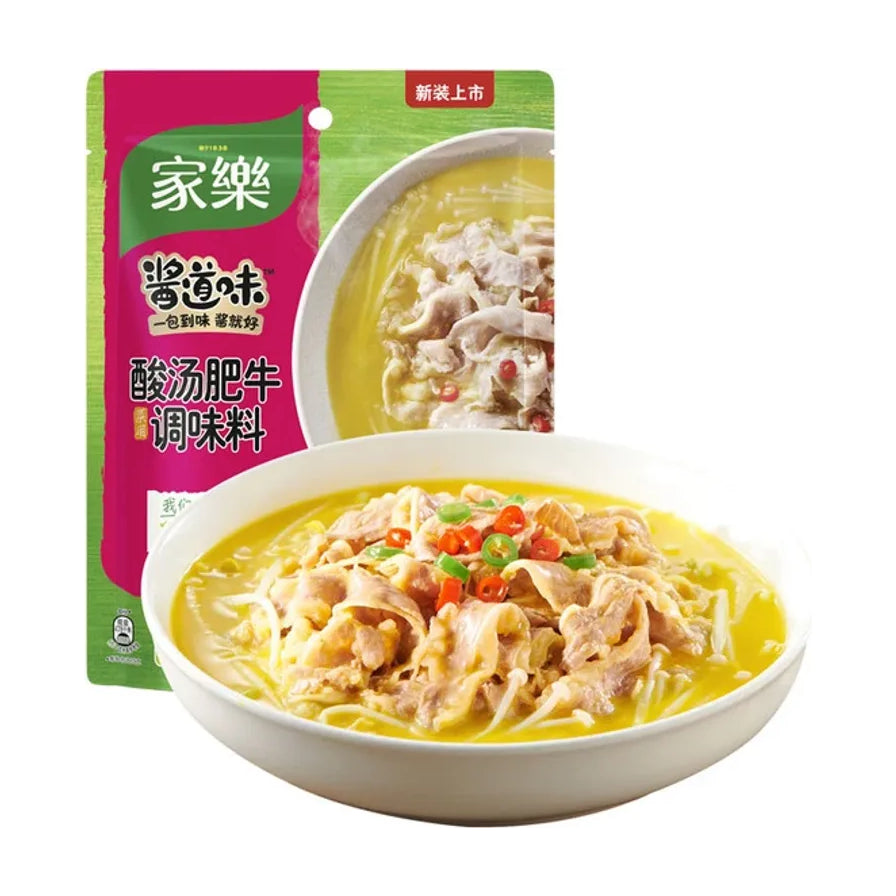 家乐酸汤肥牛调味料包装袋，背景为一碗煮好的金汤肥牛，色泽金黄诱人，配有辣椒圈点缀。