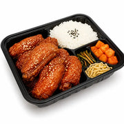 韩式炸鸡翅便当盒，包含裹满酱汁的韩式炸鸡翅、白米饭、腌萝卜和时蔬配菜，黑色分格餐盒盛装。