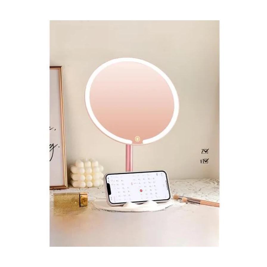 LED 化妆镜桌面场景图，展示手机支架功能，镜子置于梳妆台，前方放置一部智能手机。