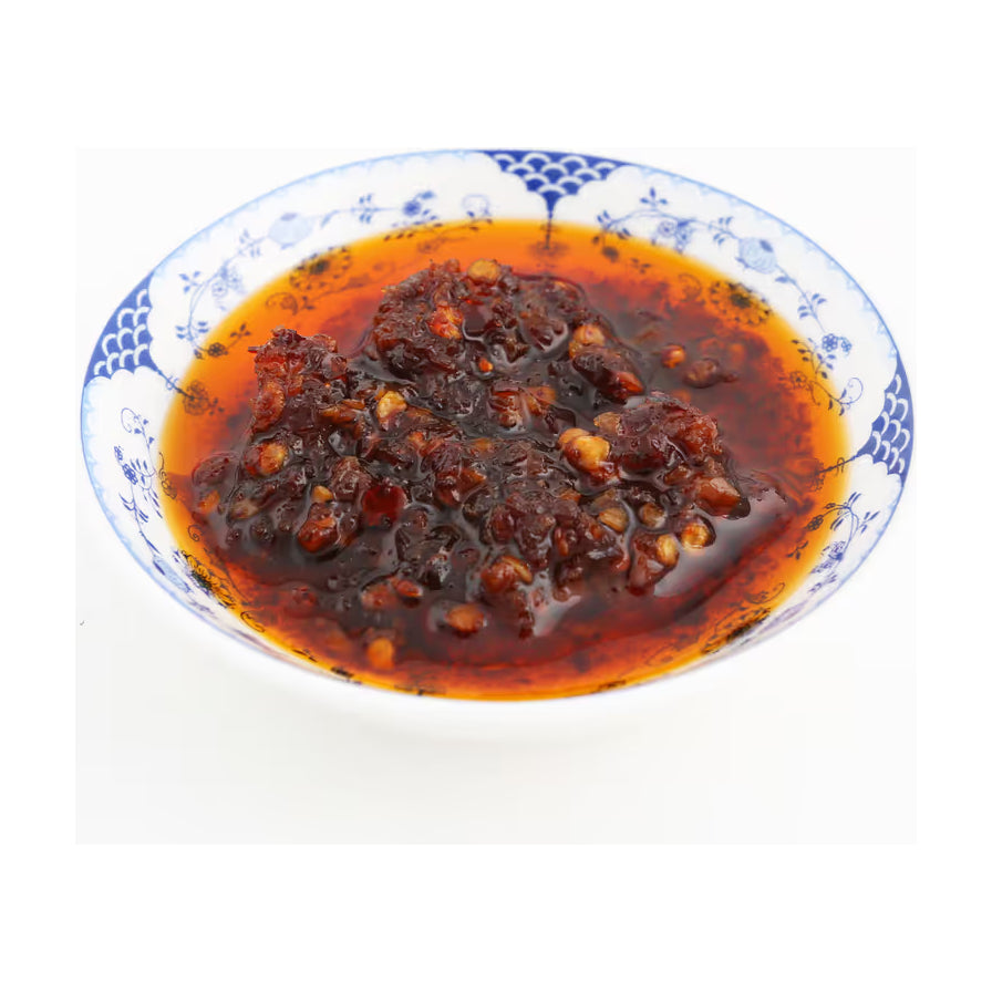 盛在青花瓷小碟中的李锦记潮州辣椒油近距离特写，展示浓郁的红油、辣椒碎和大蒜颗粒质地。