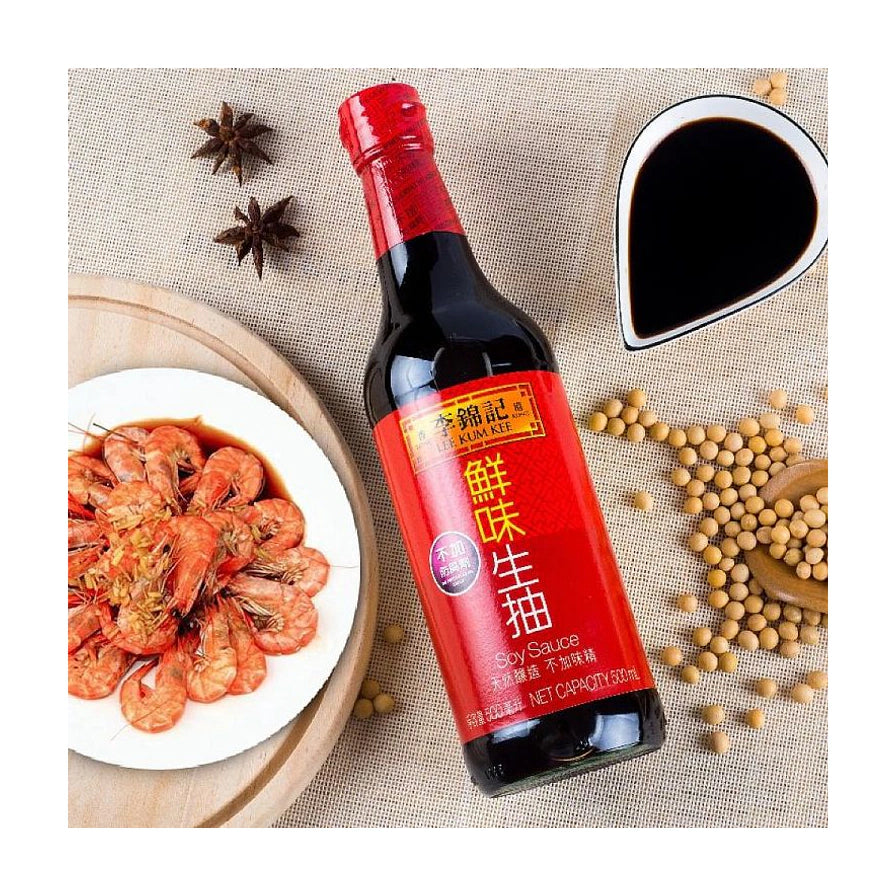 李锦记鲜味生抽瓶装斜放展示，背景配有大虾料理、黄豆和八角等食材。