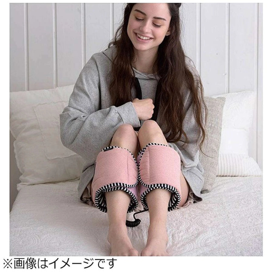 一名女性坐在床上使用粉色 LOURDES 腿部按摩器，按摩器包裹在小腿处，底部带有日文说明文字。