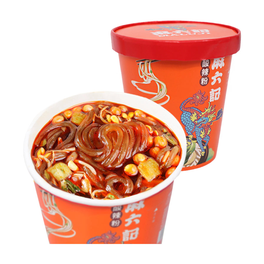 麻六记酸辣粉冲泡后实拍图，红油汤底中可见红薯粉条、花生和配菜，背景为产品包装桶。